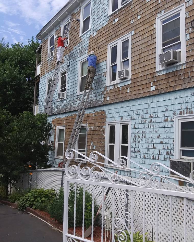 Peeling paint and exposed cedar shingles before repainting